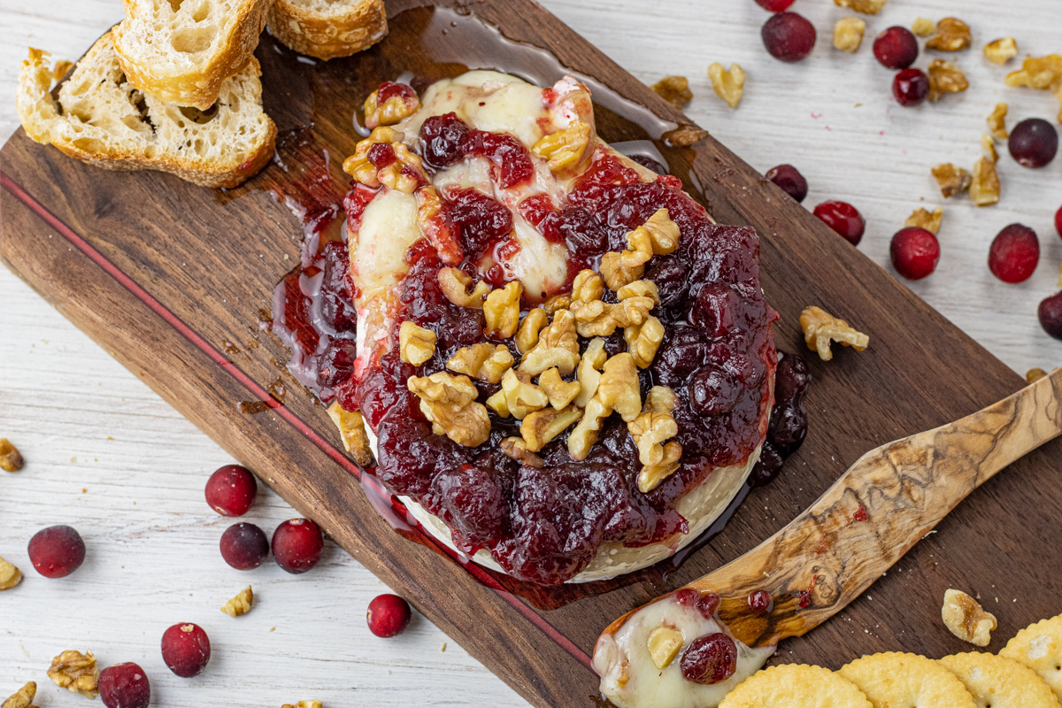 brie wheel topped with cranberries and walnuts, spilling out melted cheese