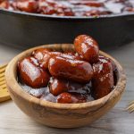 wooden bowl of mini sausages covered in bbq sauce