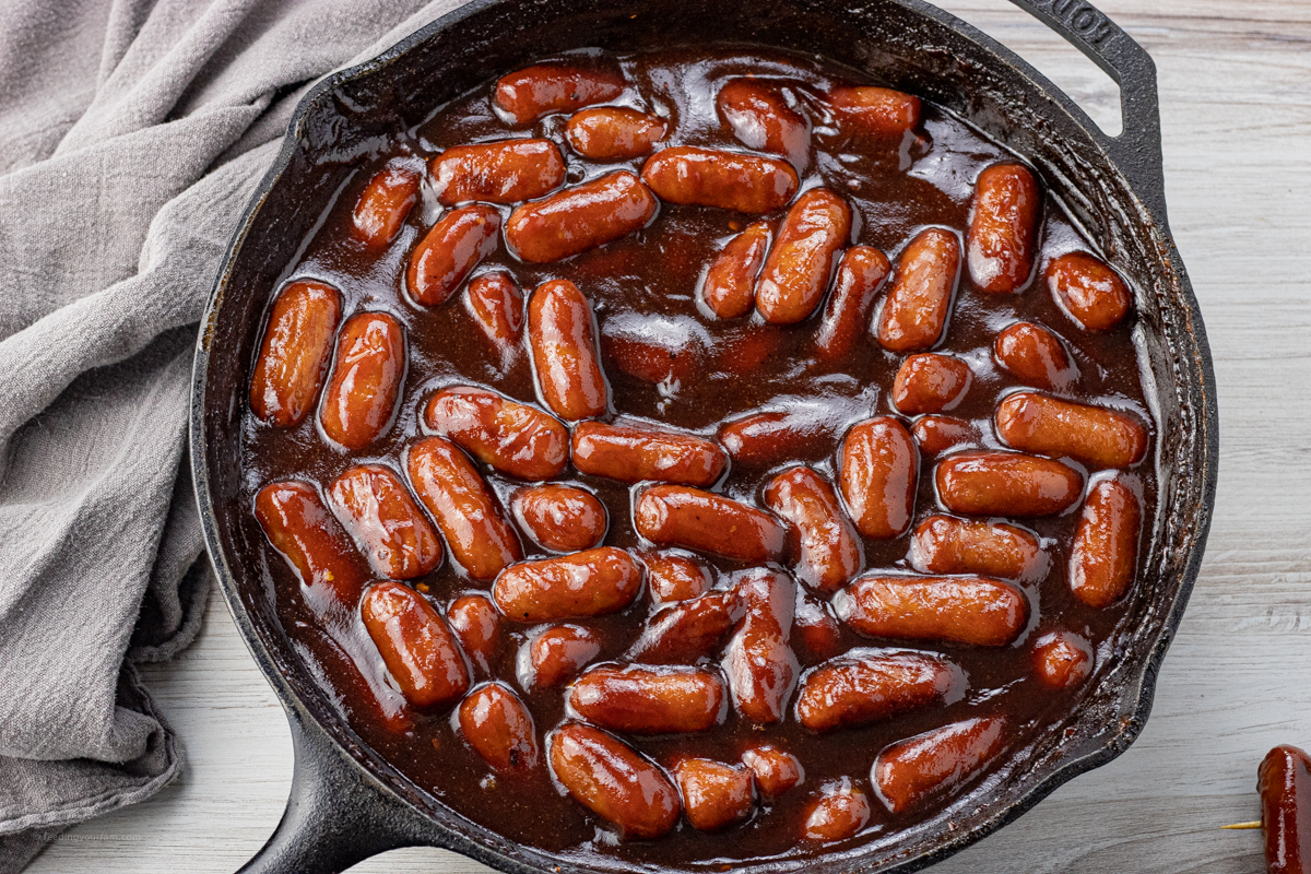 lil smokies covered in bbq sauce in a cast iron pan