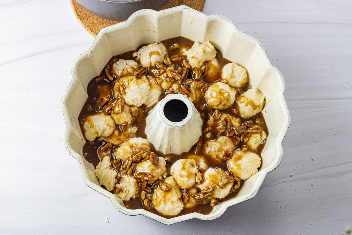 bread dough balls in a bundt pan topped with caramel sauce