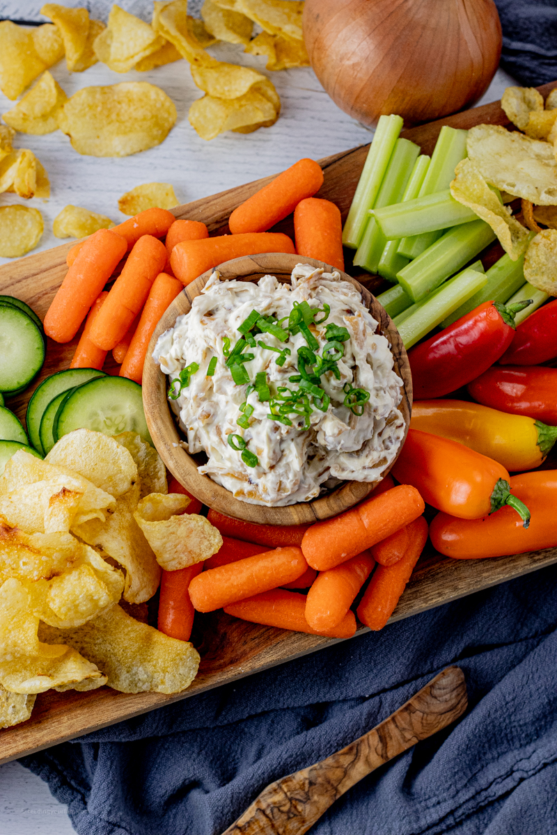 cream cheese onion dip surrounded by veggies and chips