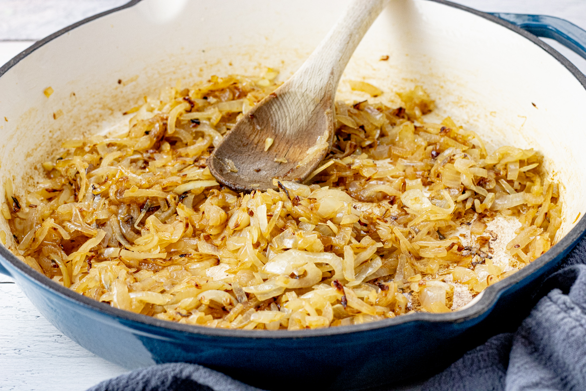 blue pan with caramelized onions and a wooden spoon