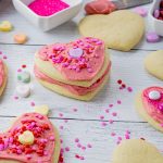 heart shaped sugar cookies with pink frosting and valentines candies