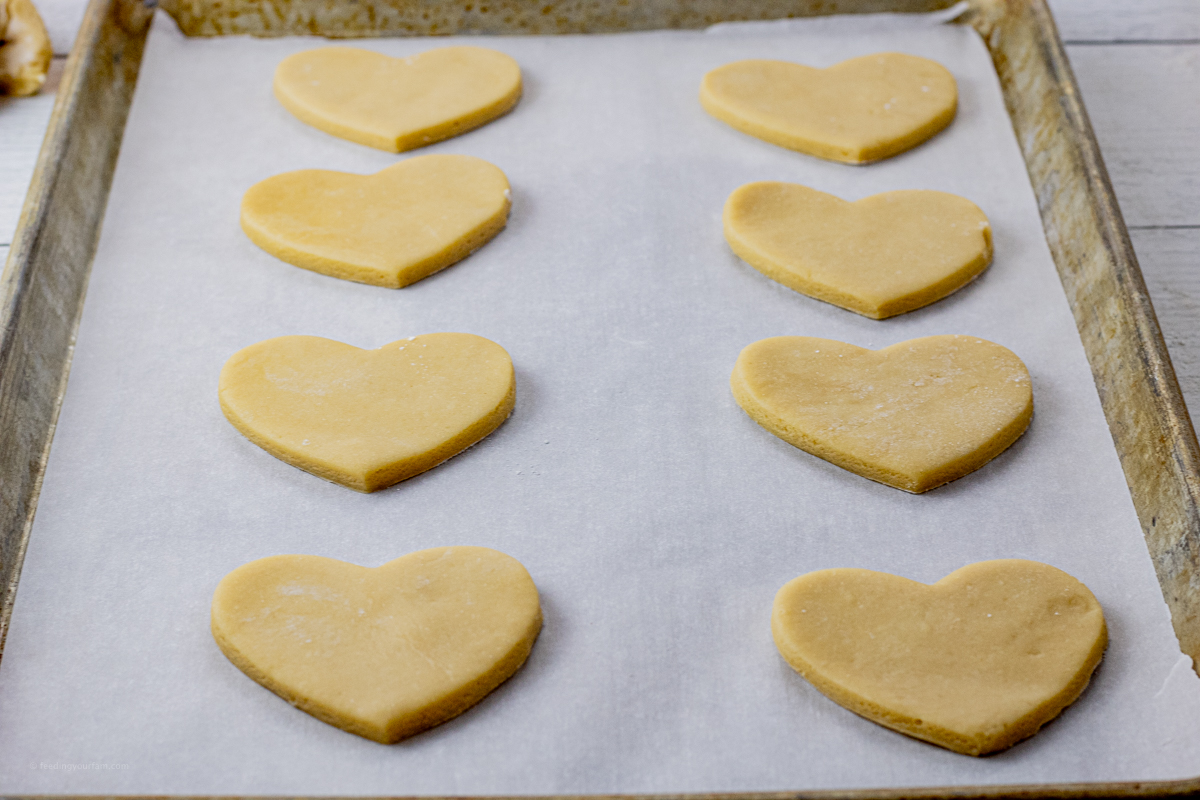 heart shaped cookie dough on a parchment lined baking sheet
