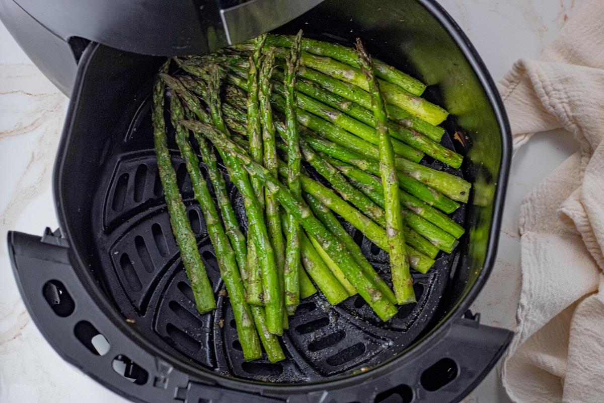 dark green, cooked asparagus spears in the bottom of an air fryer basket