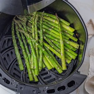 cooked asparagus spears in the basket of an air fryer