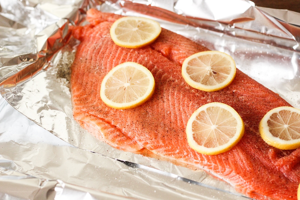 uncooked salmon, topped with lemon slices on a piece of foil