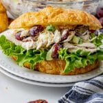 chicken salad with red grapes inside of a buttery croissant with leafy lettuce