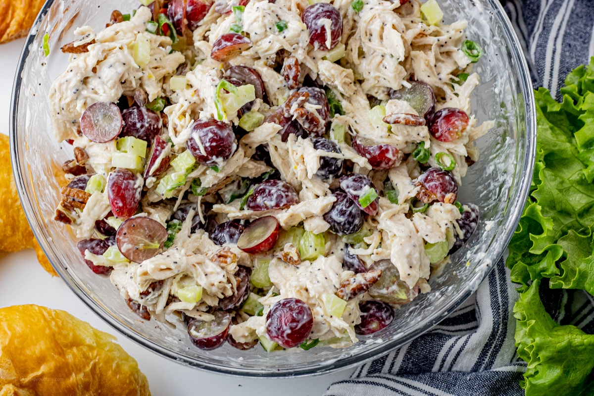 shredded chicken salad with red grapes in a glass mixing bowl