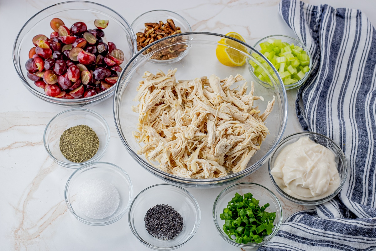 ingredients for chicken salad separated out into smaller glass mixing bowls