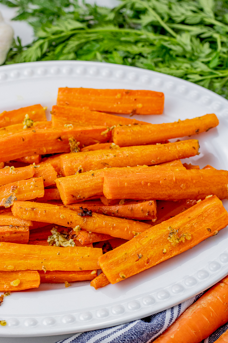sliced orange carrots with garlic and parmesan pieces on the carrots on a white serving platter