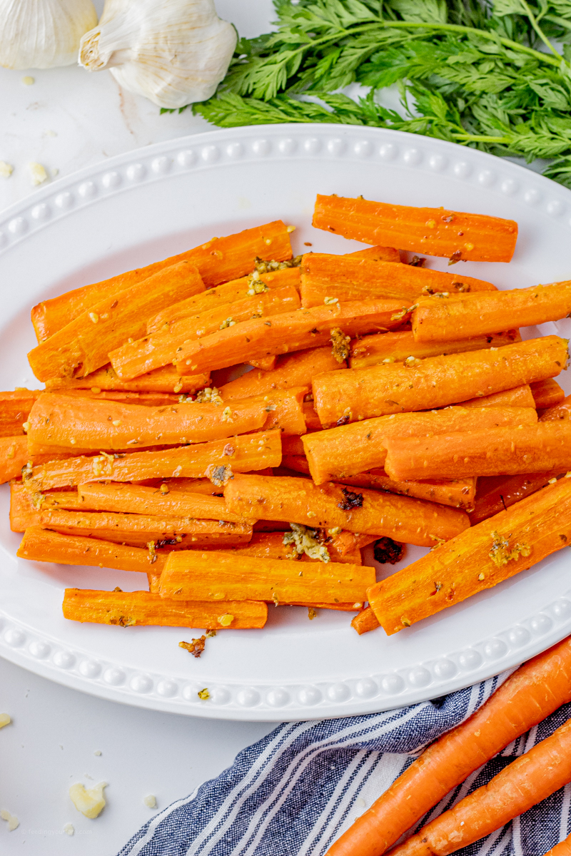 sliced, cooked carrots with garlic and parmesan on a white serving platter