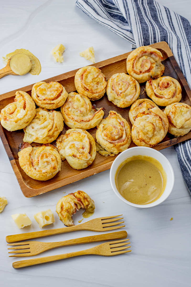 flaky ham and cheese swirled in puff pastry on a wooden serving platter