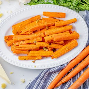 sliced, roasted carrots with parmesan and garlic on a white serving plate