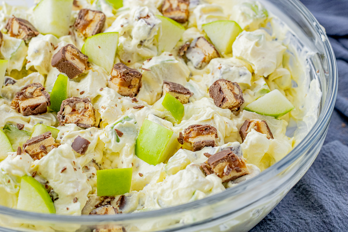 glass mixing bowl filled with a pudding, snickers and green apple mixture