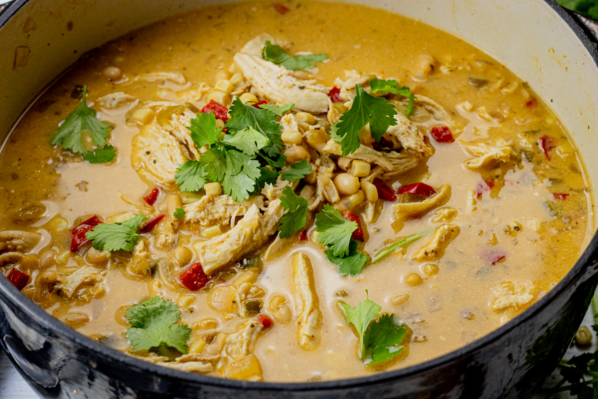 big black pot of white chili with chicken topped with cilantro