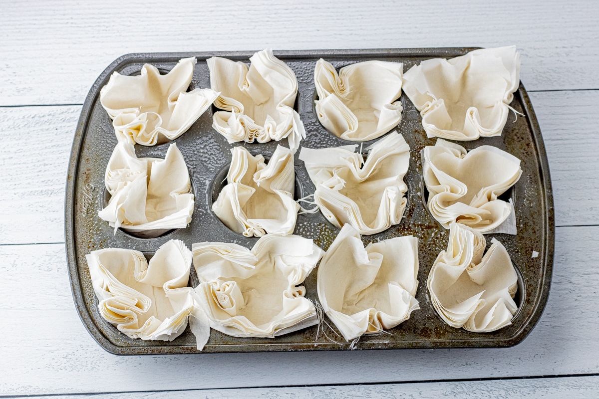 uncooked phyllo dough sheets in a muffin tin