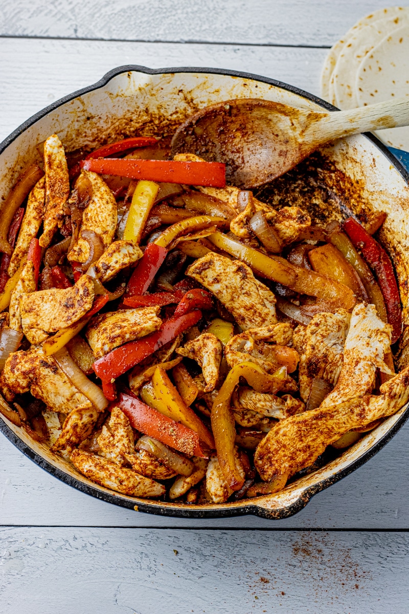 chicken and peppers in fajita seasoning in a large skillet