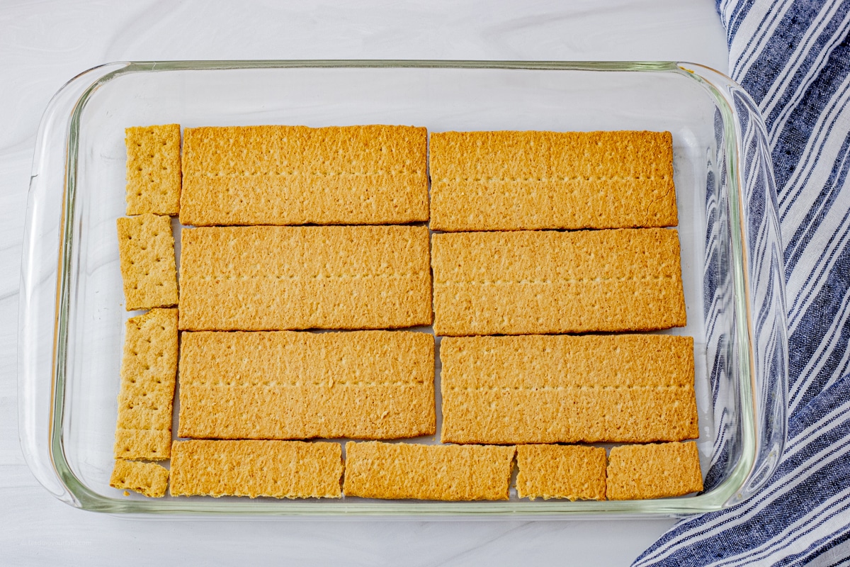 glass baking dish with a layer of graham crackers on the bottom of the pan