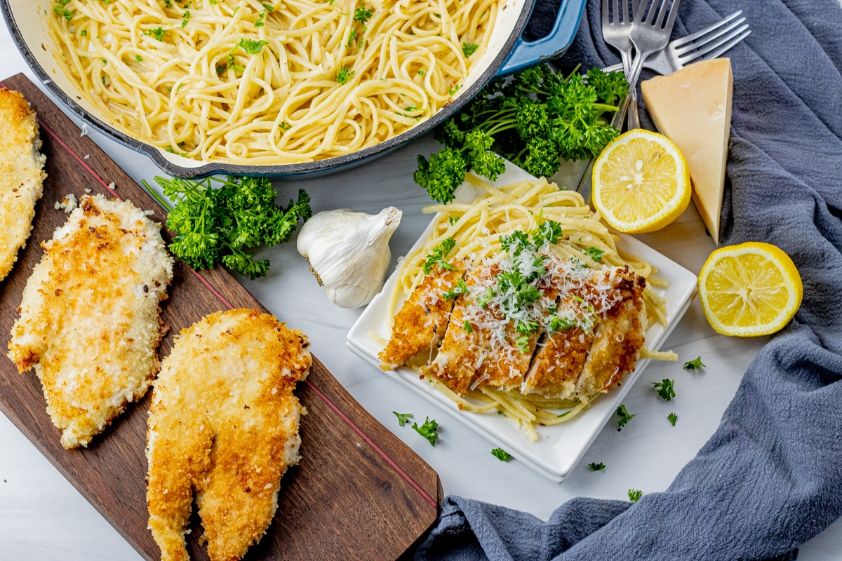chicken cooked with panko bread crumbs on a wooden cutting board and another over pasta