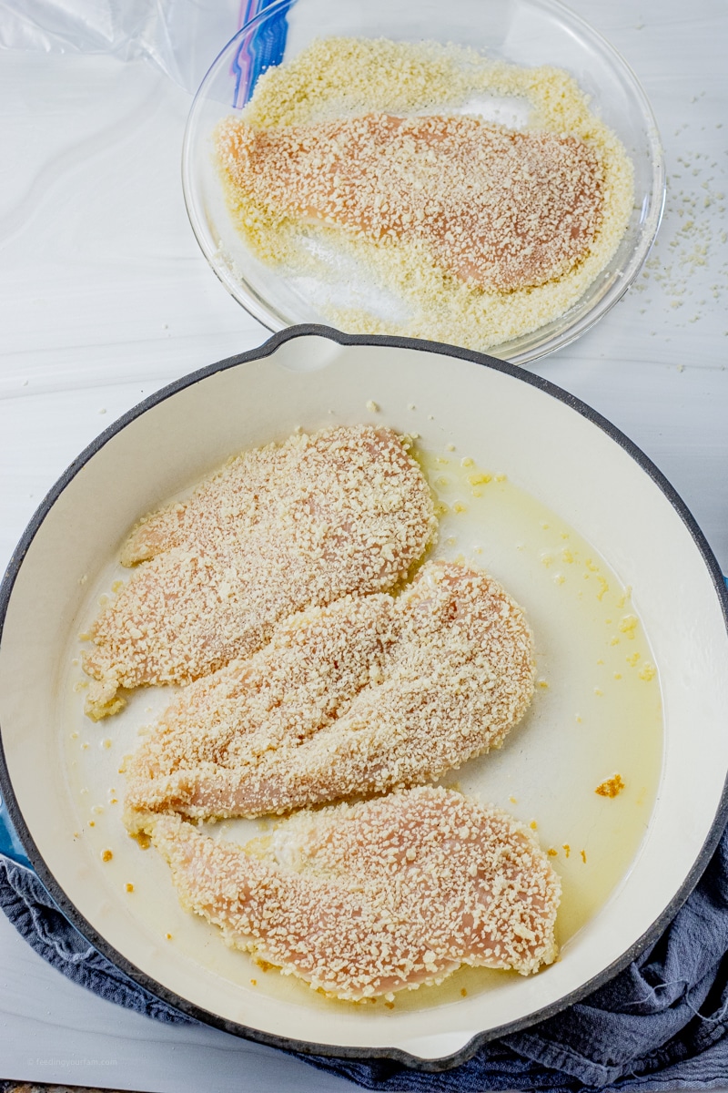 chicken coated in bread crumbs cooking in a cast iron pan