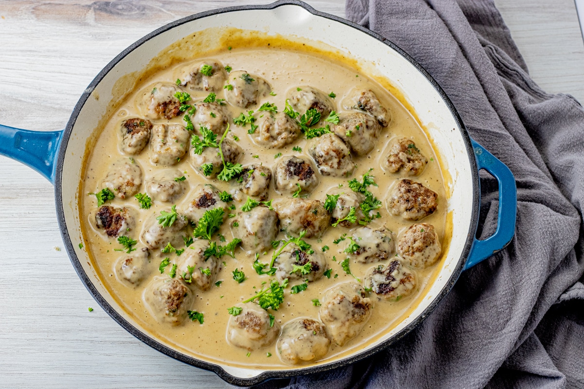 cooked swedish meatballs in a brown gravy sauce in a large cast iron pan