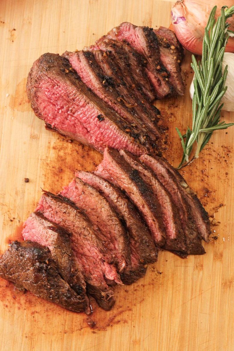 sliced tri tip roast cooked to medium rare on a wooden cutting board