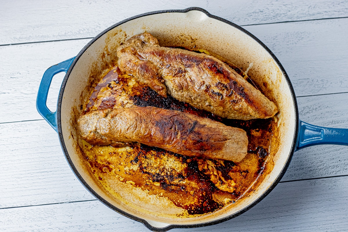 two pork tenderloins browned in a cast iron pan