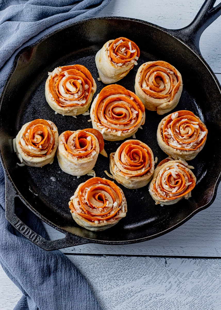 uncooked rolls made with pepperoni and mozzarella cheese in a cast iron pan