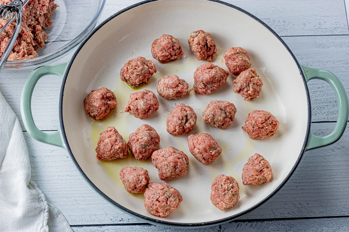 rolled meatballs in a large, round enameled cast iron pan