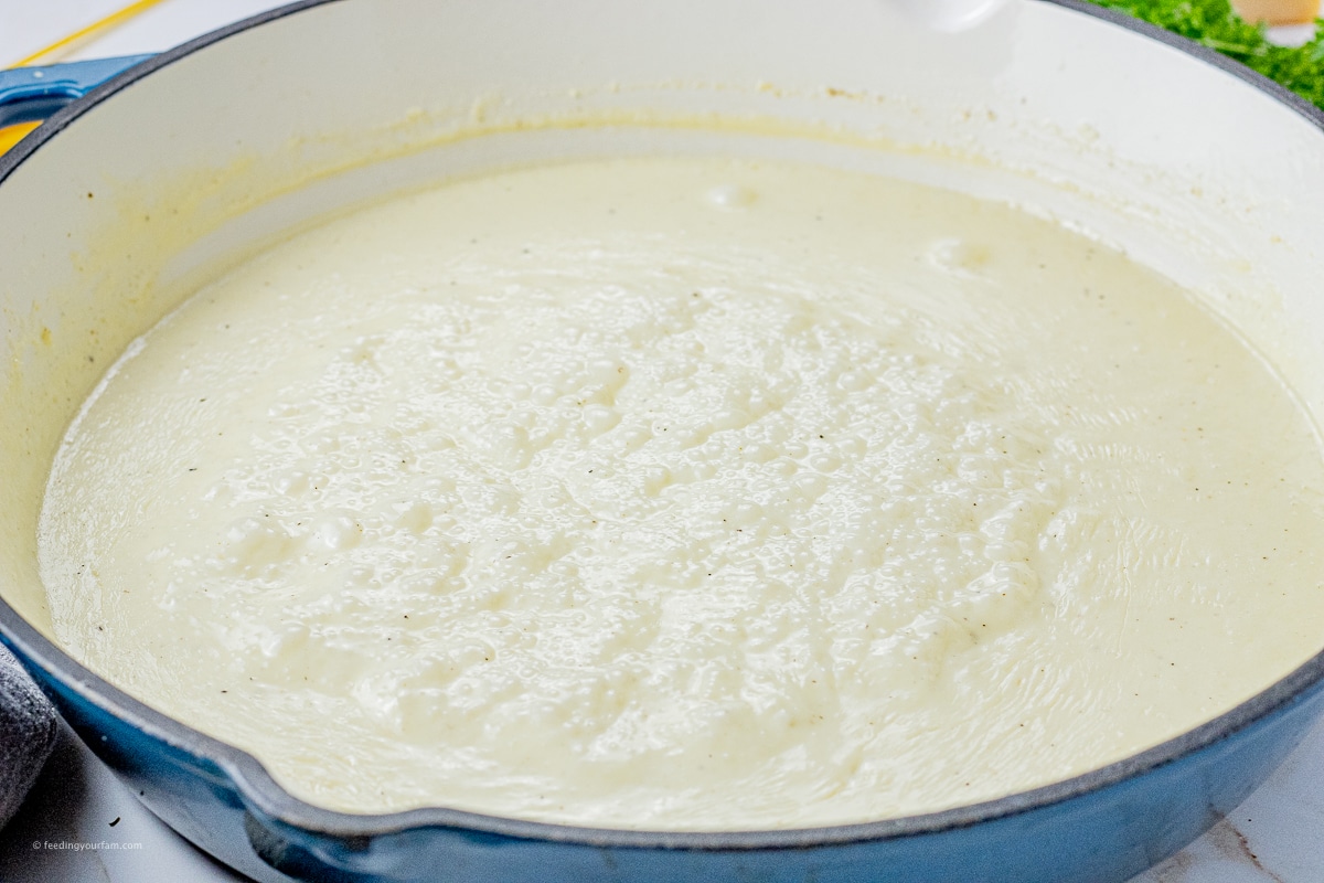 simmering alfredo sauce in a large skillet