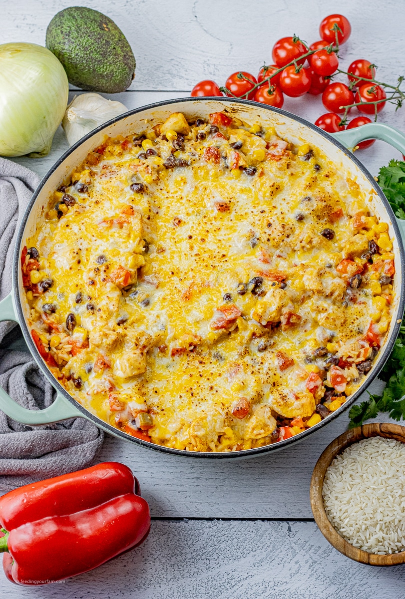 large skillet with black beans, rice, tomatoes, corn and chicken topped with melted cheese