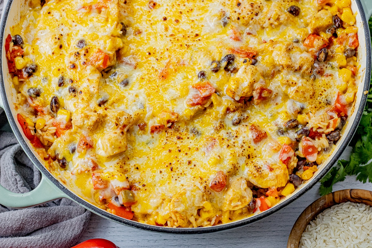 big skillet with rice, beans, chicken, tomatoes all topped with melted cheese