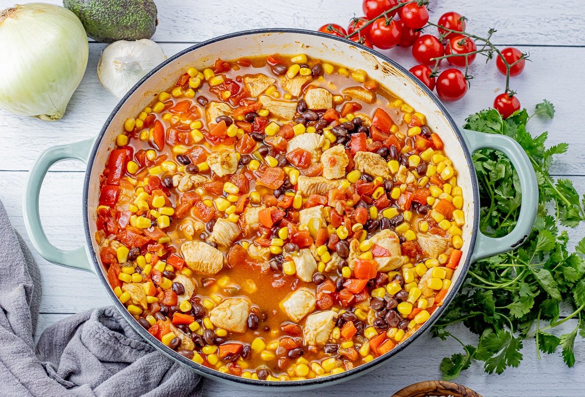 large skillet with chicken, tomatoes, corn, black beans,  rice and chicken broth