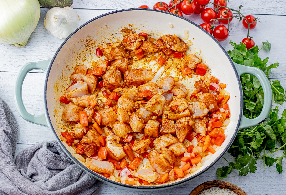 uncooked chicken, red peppers and onions in a large skillet