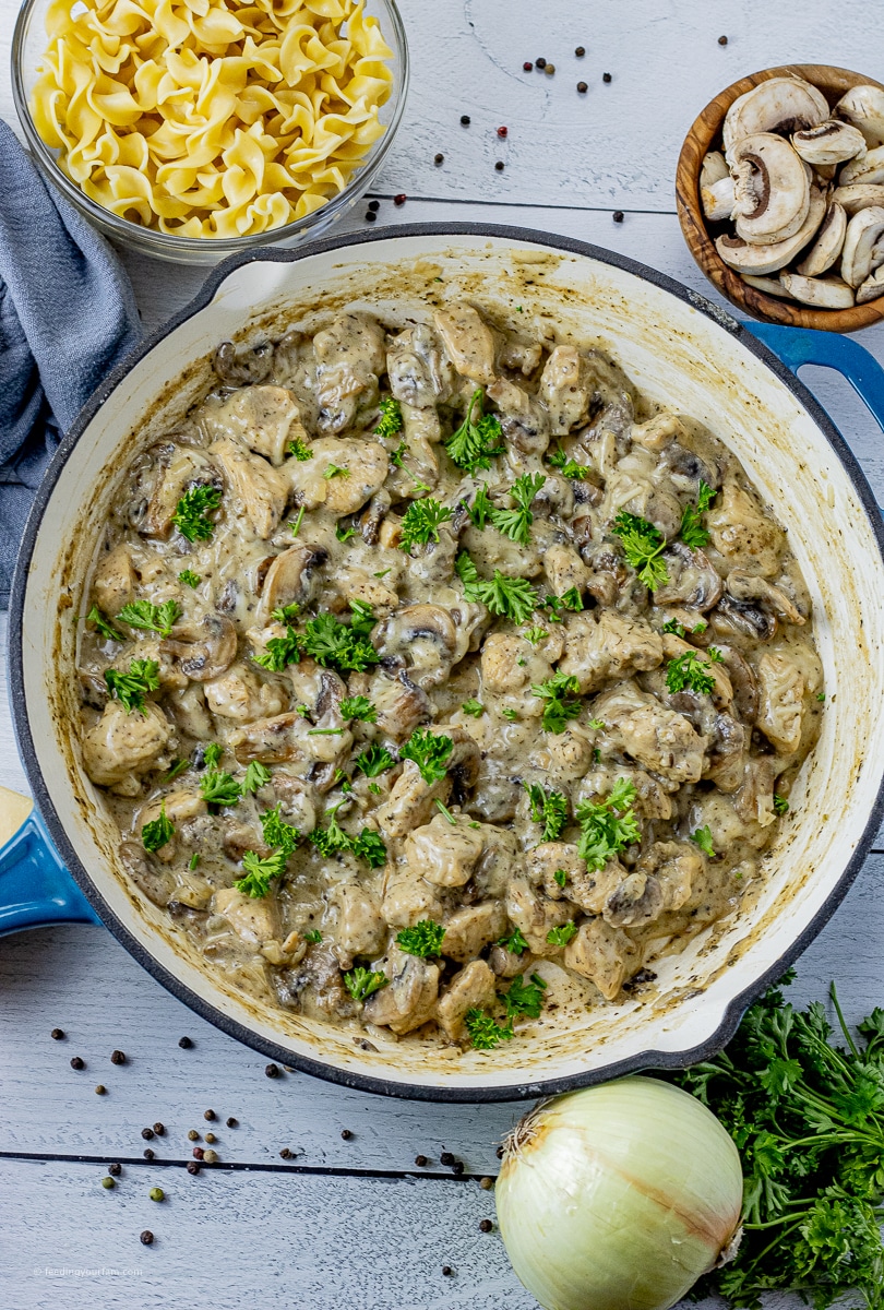 big cast iron pan of chicken with mushroom in a creamy sauce with parsley on top