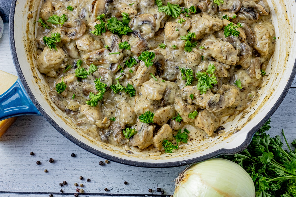 creamy mushroom sauce with pieces of chicken and parsley in a cast iron pan