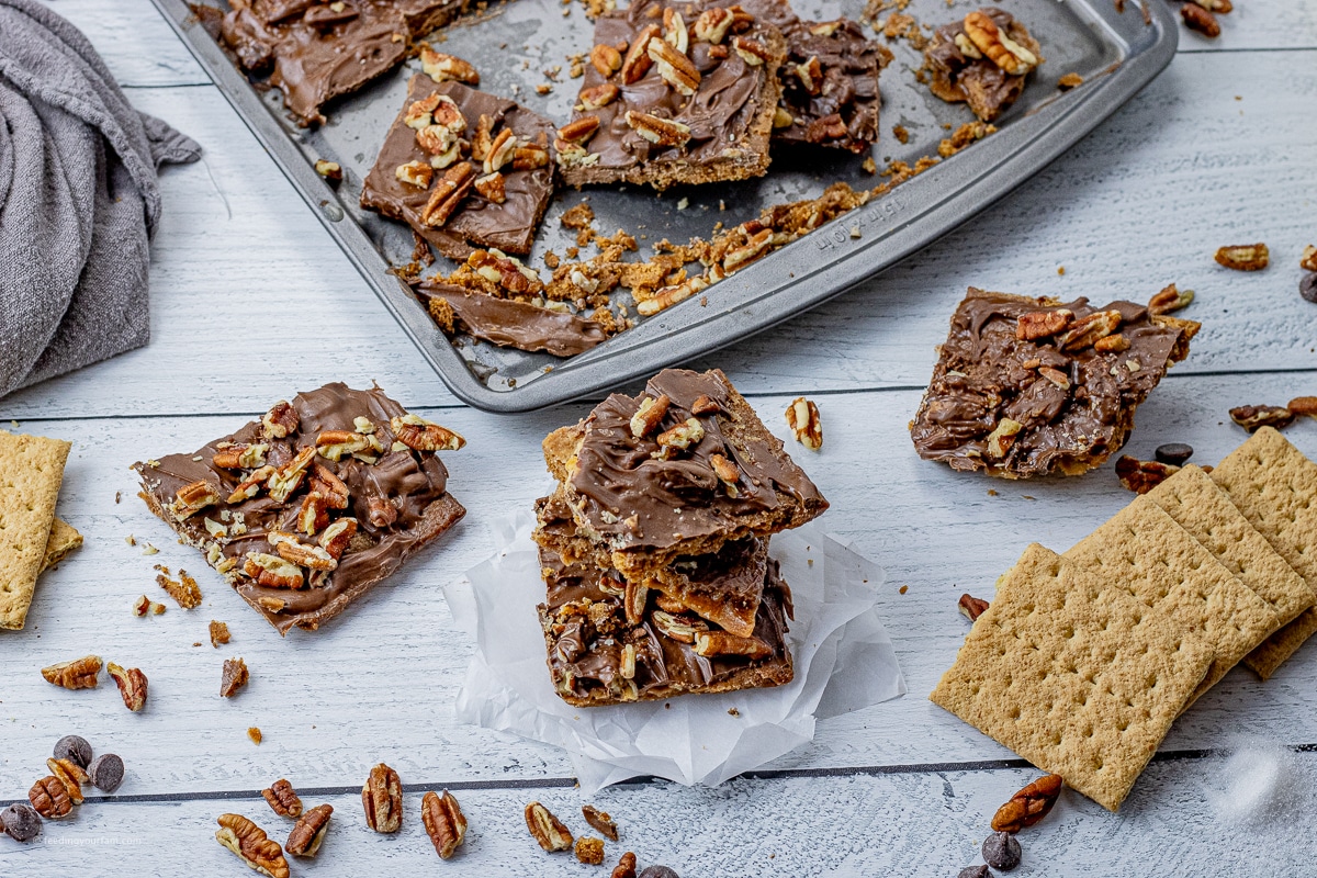 pieces of graham cracker toffee topped with chocolate and pecans