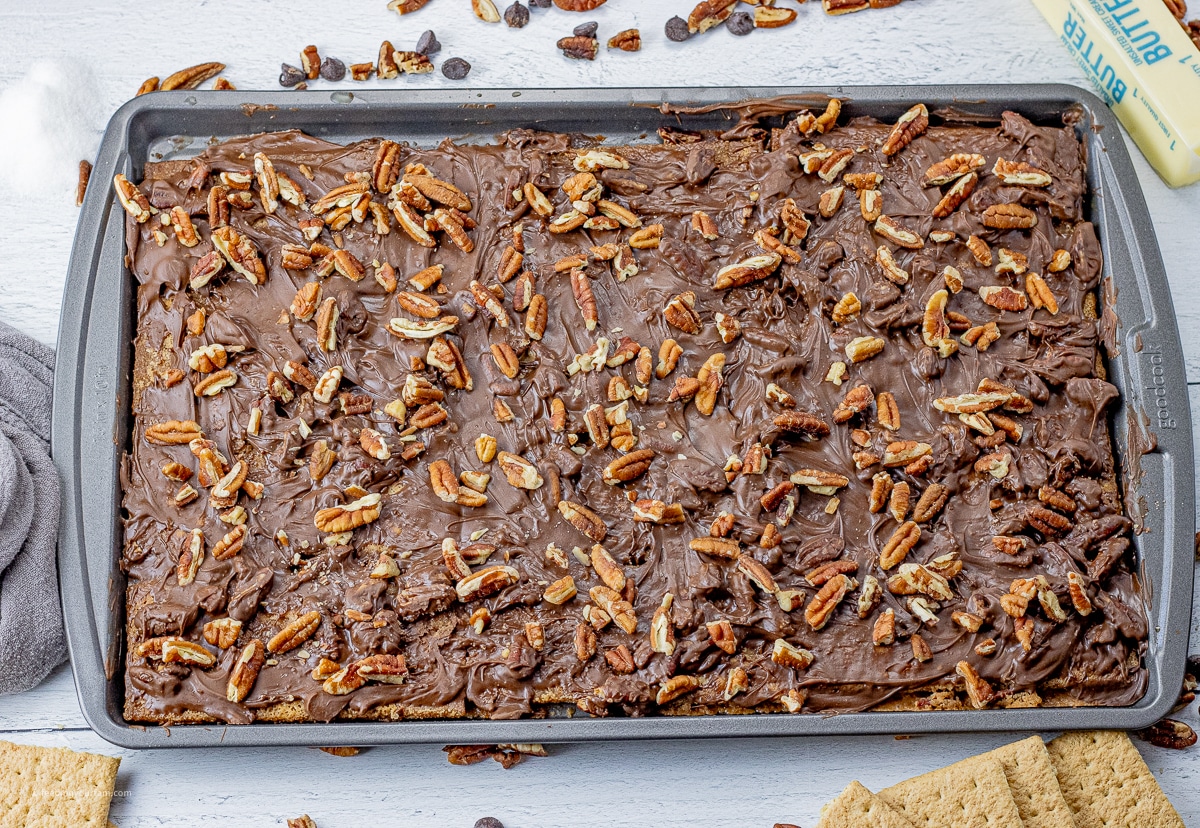 pan full of graham crackers topped with toffee, chocolate and pecans