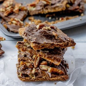 stacked pile of graham cracker toffee topped with chocolate and pecans