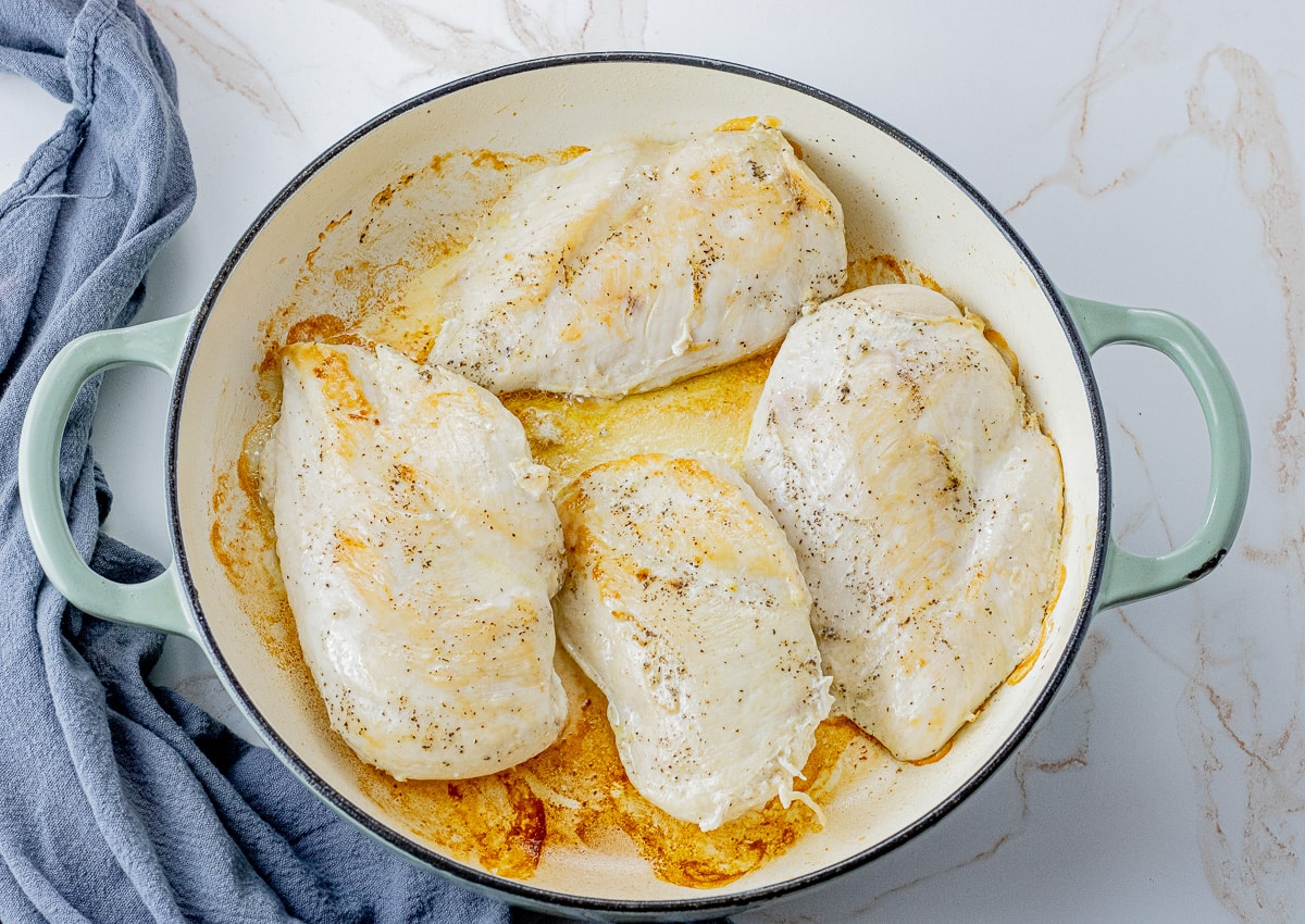 4 browned chicken breasts in a large cast iron pan