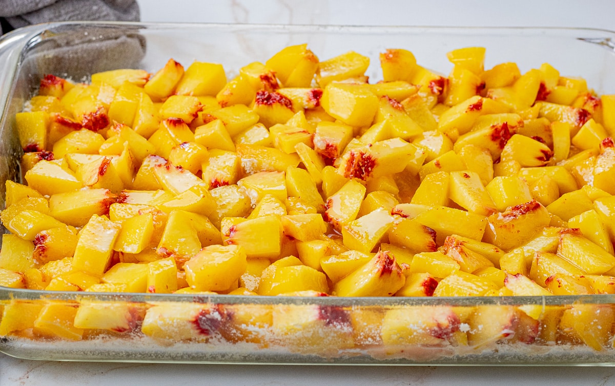diced peaches on top of shortbread crust in a glass baking dish