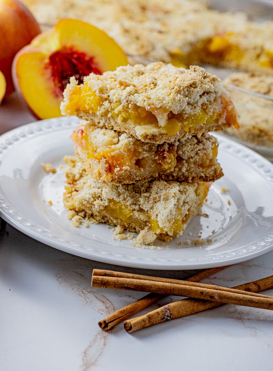 3 peach crumble bars on top of each other on a white plate