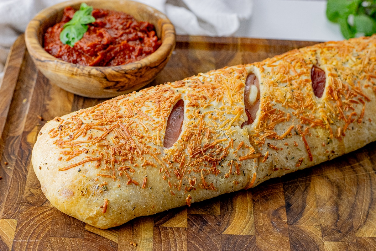 stromboli topped with melted parmesan cheese on top of a wooden cutting board