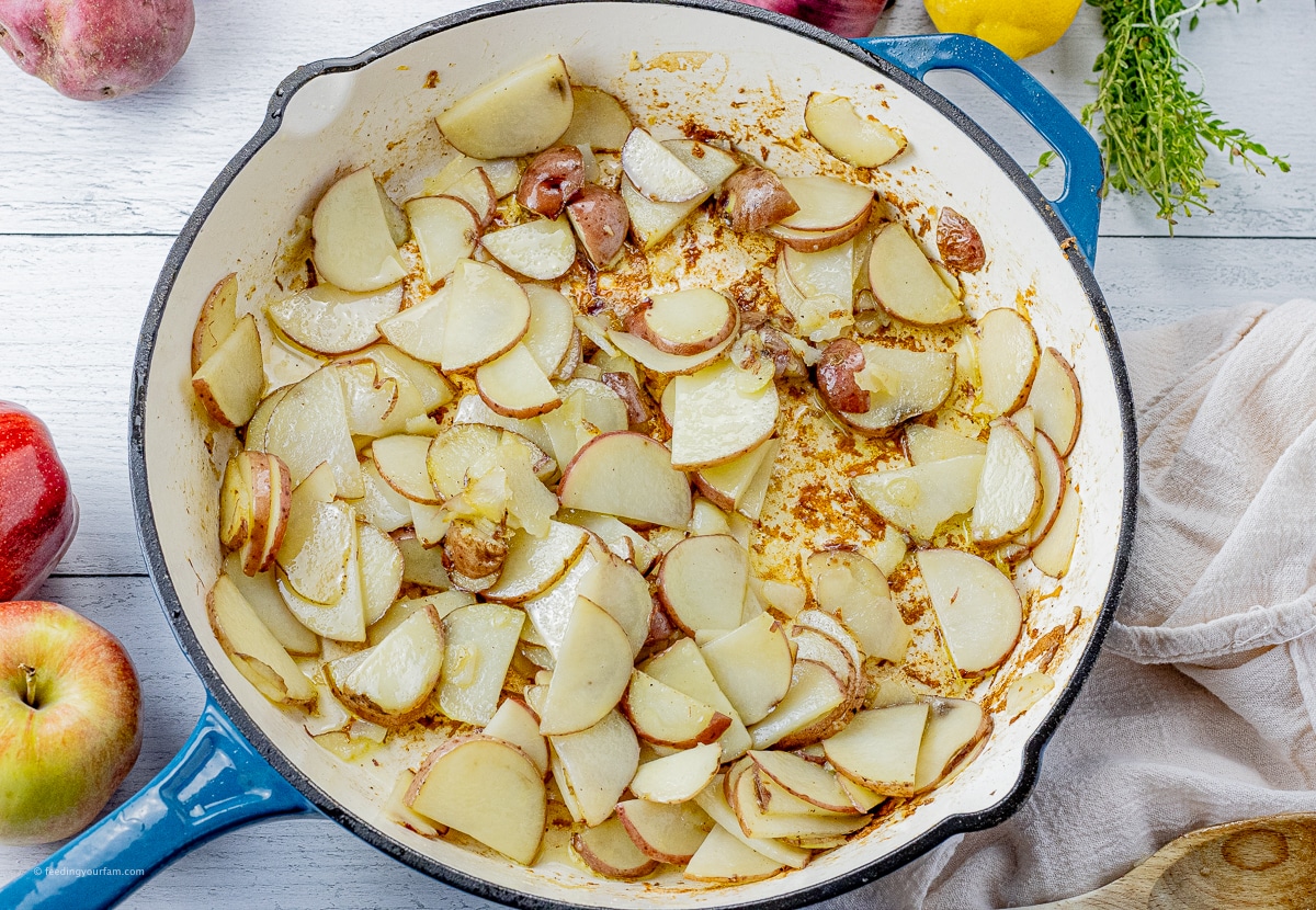 thinly sliced potatoes cooking in a large skillet