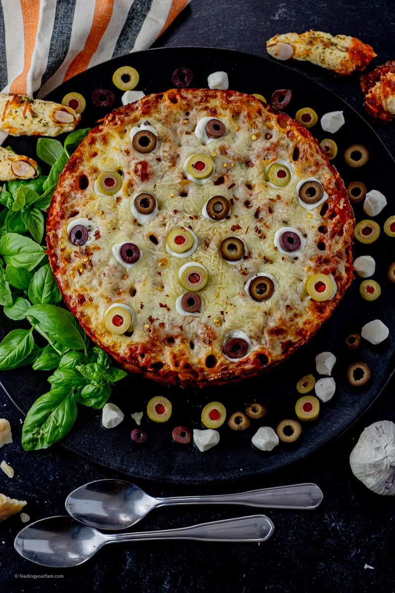 rigatoni baked into a big round, topped with cheese and sliced olives to look like eyeballs