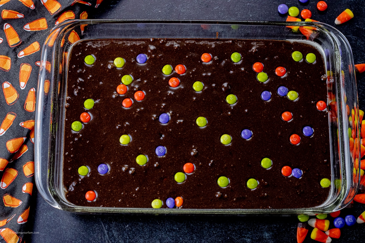 brownie batter topped with colorful candies in a glass baking dish