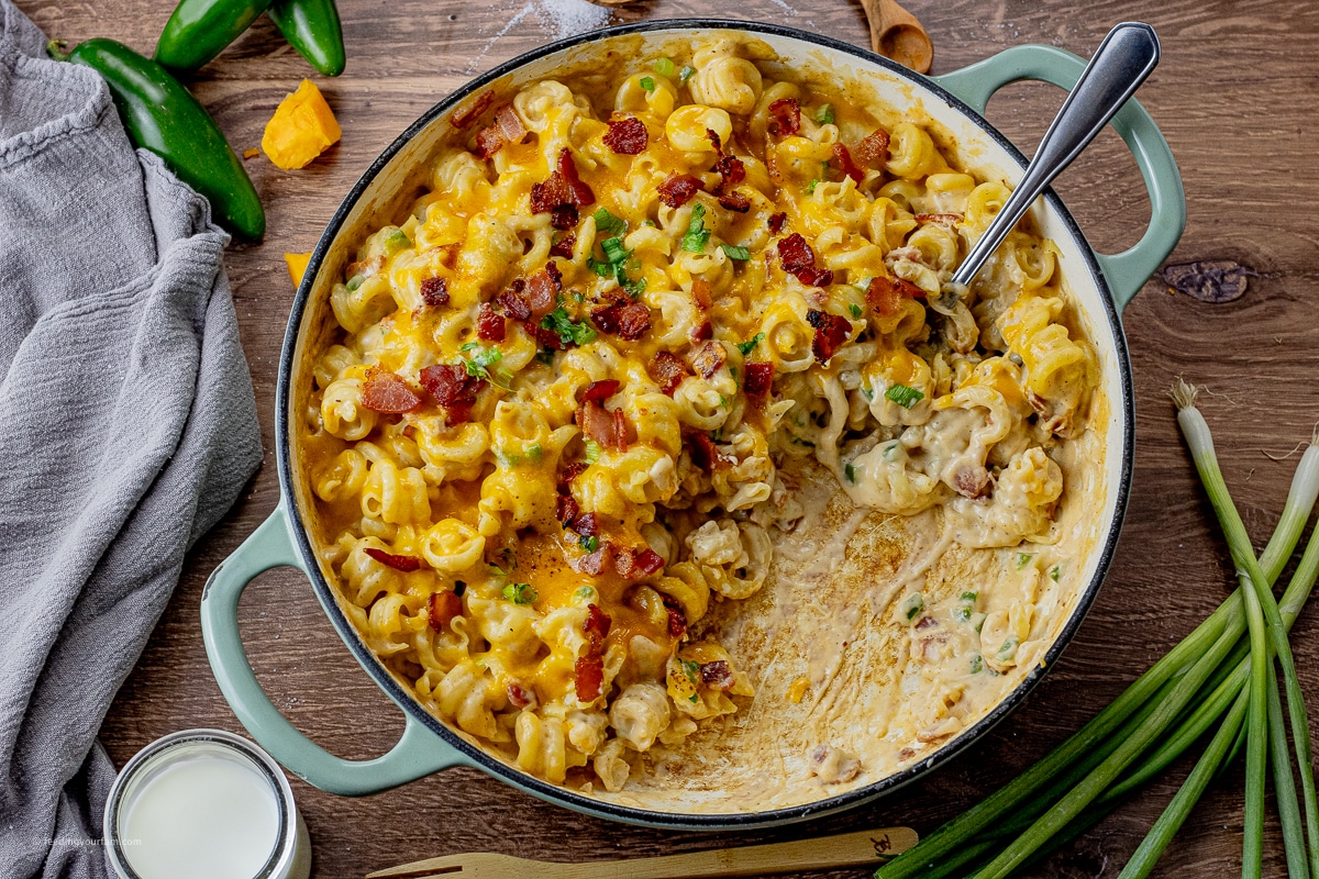 big pan of mac and cheese with bacon and jalapenos and some scooped out of the pan