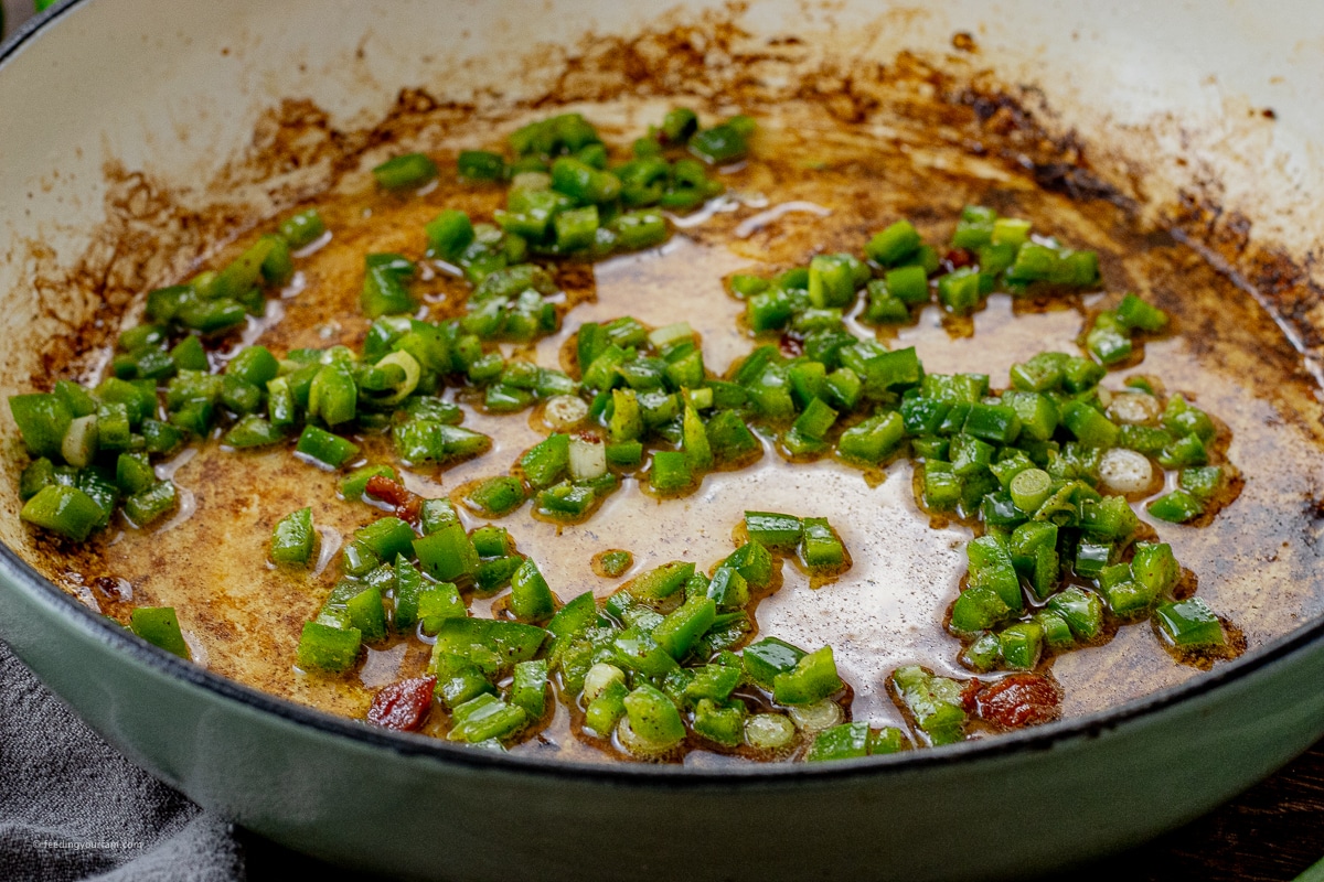 cooked jalapeno and green onions in a large pan in bacon grease