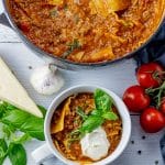 lasagna soup topped with ricotta cheese and fresh basil